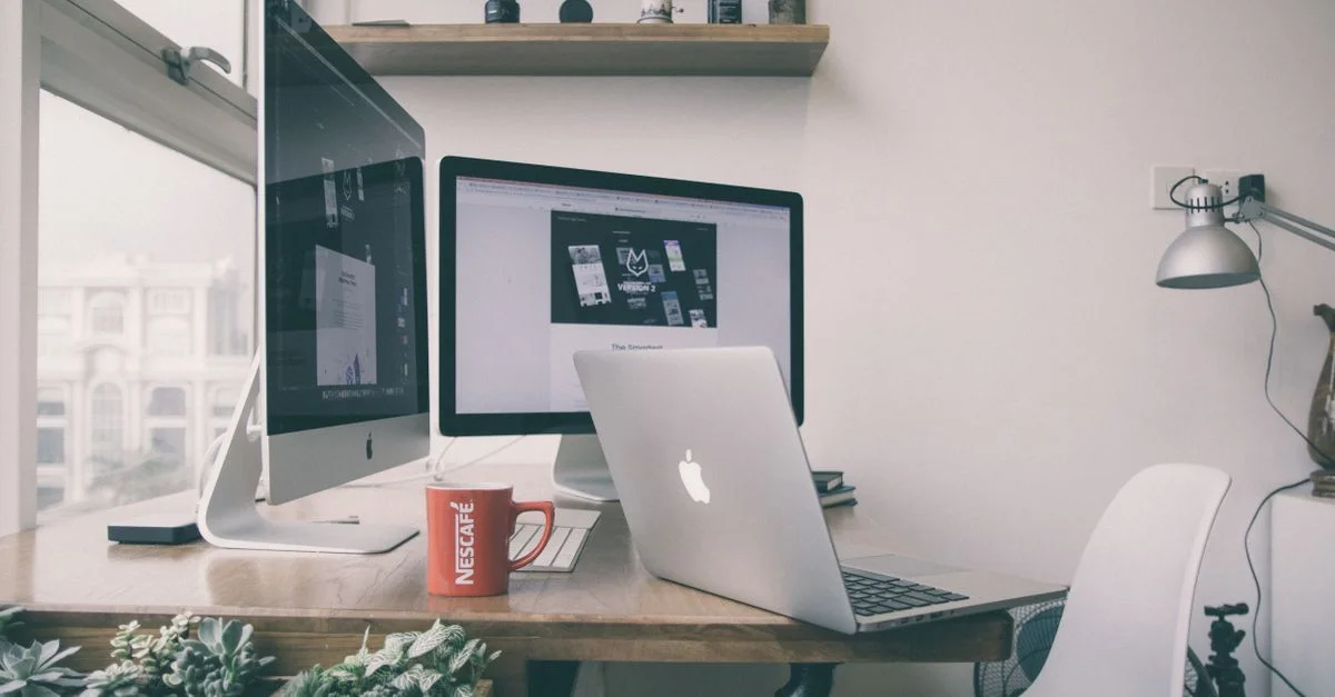 Aménagement de bureau à domicile élégant avec double moniteur, un ordinateur portable et décoration minimaliste.