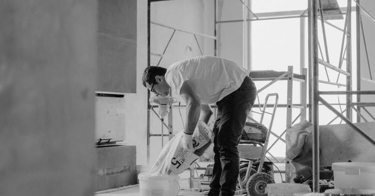 Un ouvrier du bâtiment verse des matériaux à l'intérieur d'un bâtiment en cours de rénovation.