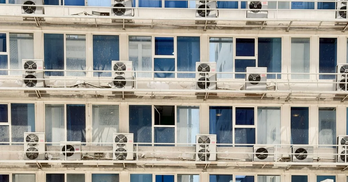 Gros plan sur l'extérieur d'un bâtiment moderne avec des climatiseurs à chaque étage.